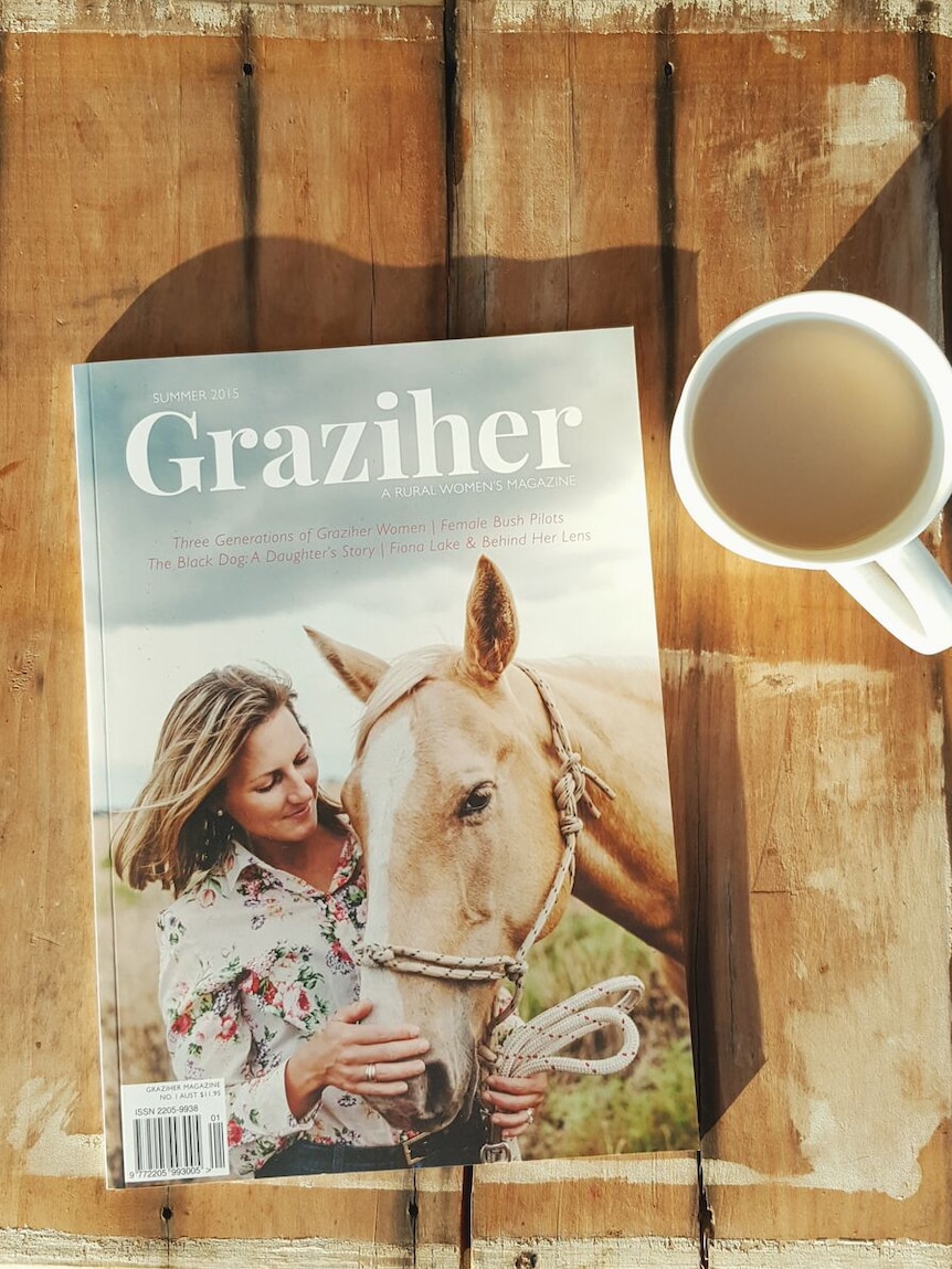 A magazine, called Graziher, sits on a table with a teacup.