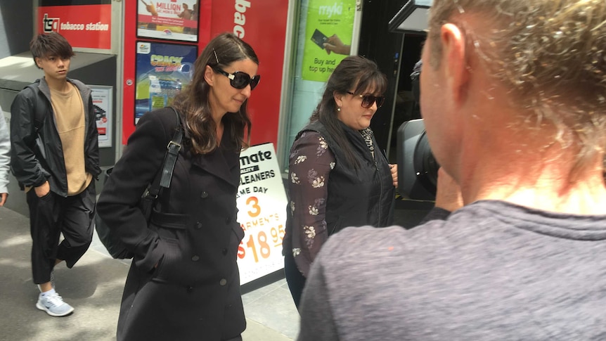 Irene Moschones, with hands in pockets, in dark glasses, walks past a newsagency as she leaves court.