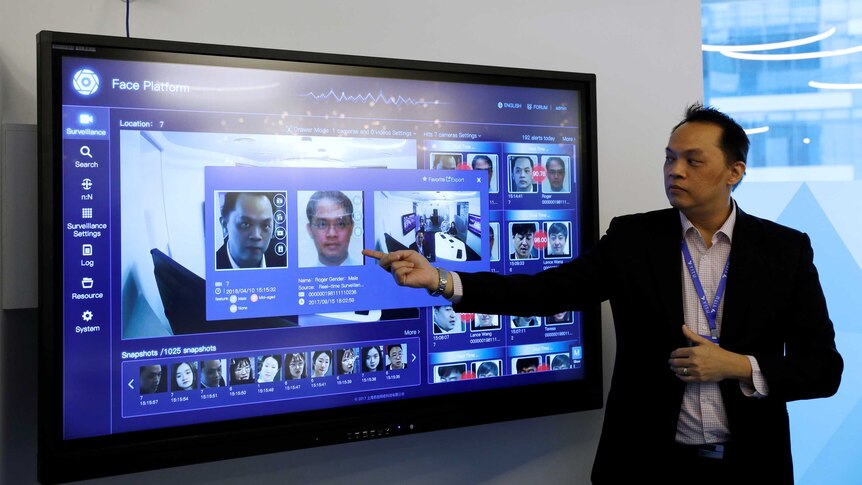 A Yitu employee points a screen showing the company's face recognition technology
