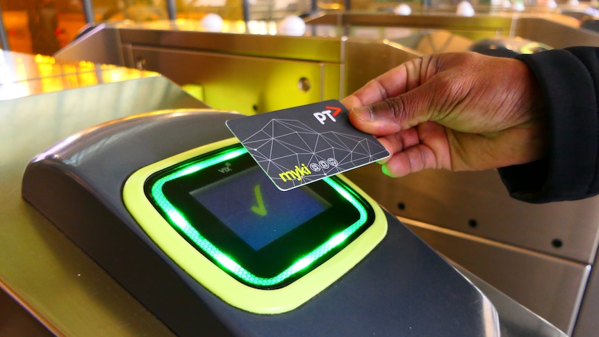 A hand tapping a myki public transport card onto a turnstile