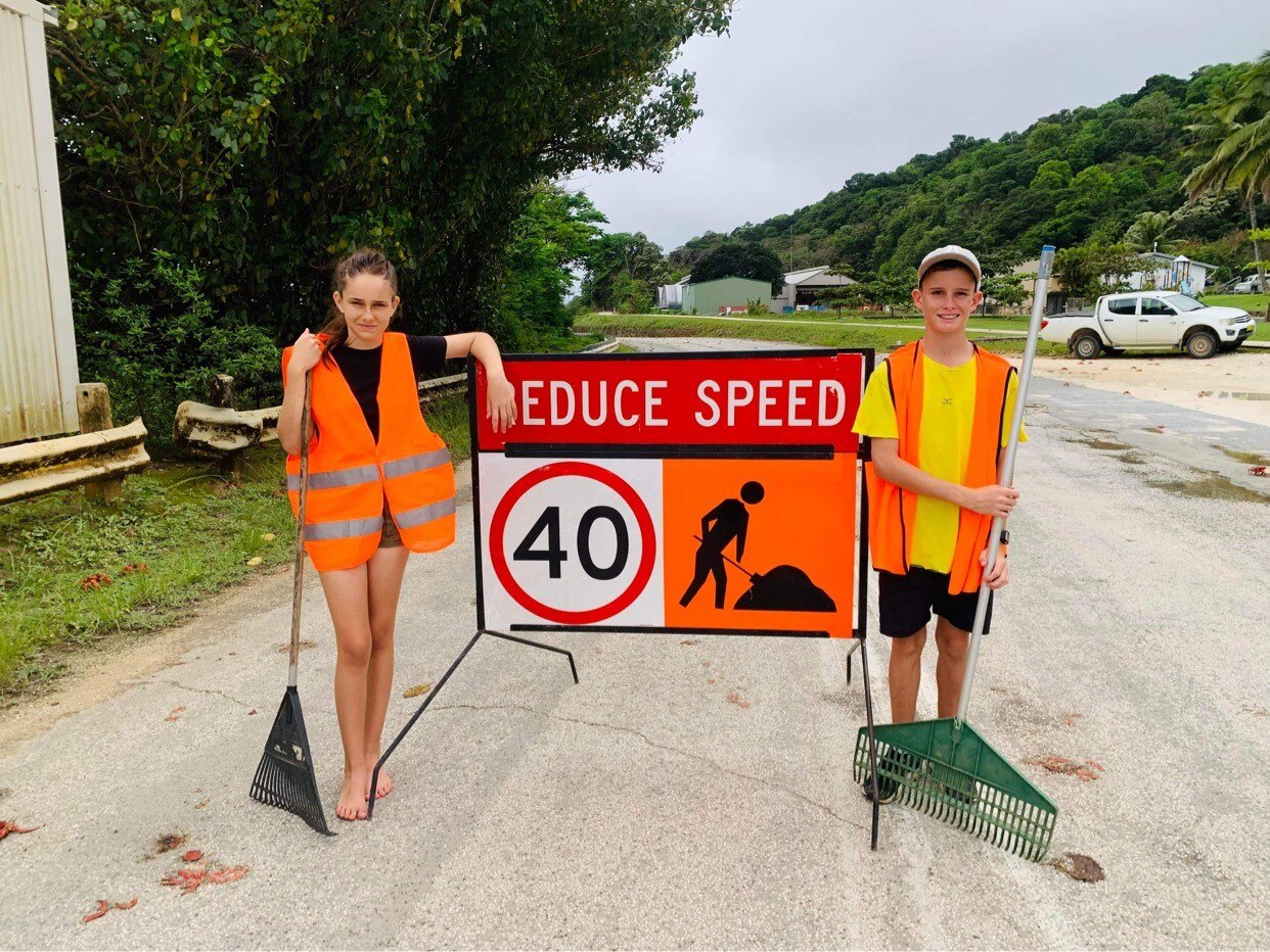 Christmas Island kids Ashleigh Collis and Mitchell McKnight holding rakes