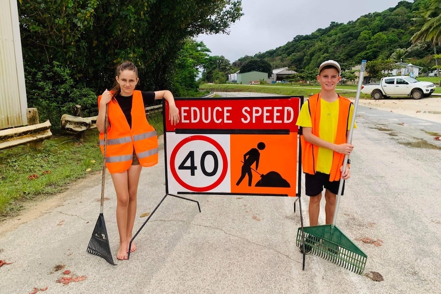 Christmas Island kids Ashleigh Collis and Mitchell McKnight holding rakes