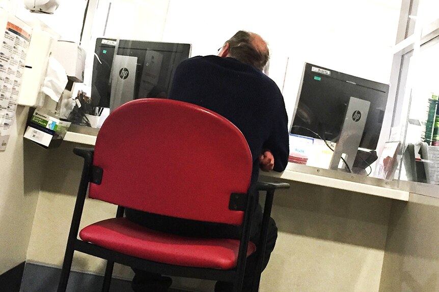 A man sits at Royal Hobart Hospital emergency reception counter.