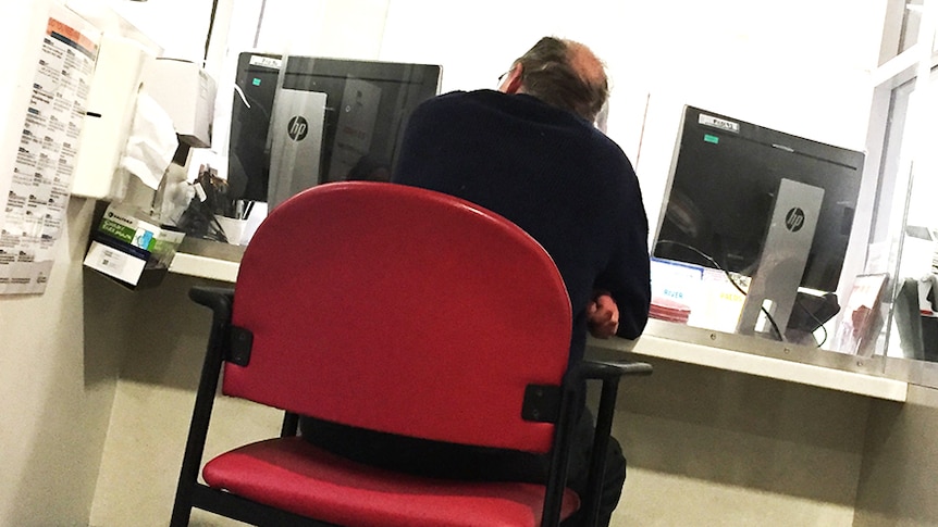 A man sits at Royal Hobart Hospital emergency reception counter.