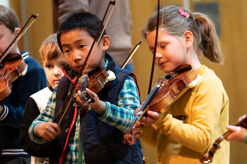 Young children playing violins.
