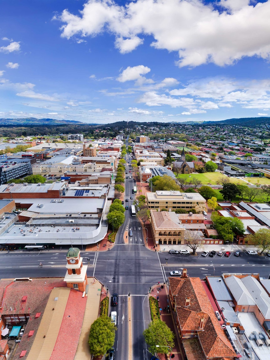 Aerial overhead view of regional town with hills in the background.