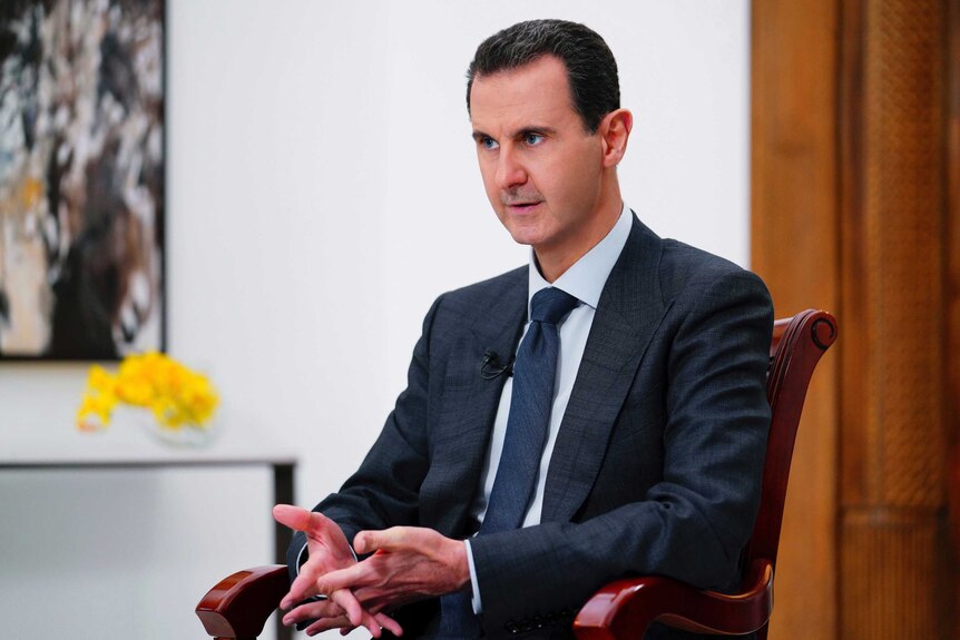 Syrian President Bashar Assad speaks to the camera wearing a suit.