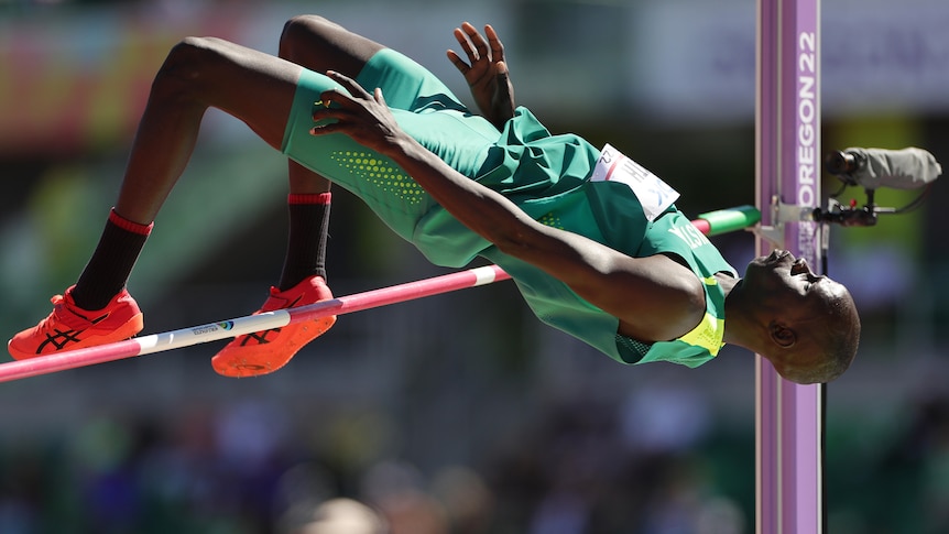 A men's high jumper arches his back as he tries to clear the high jump bar at a major athletics championship.