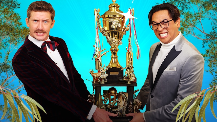 triple j's Lewis Hobba and Michael Hing dressed in suits and clutching a giant gold trophy cup