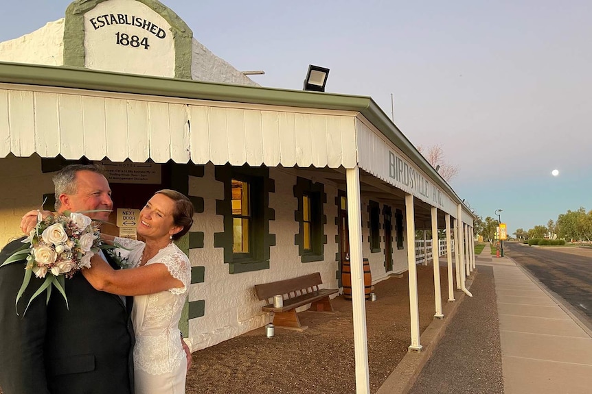 A wedding couple embrace out the front of the Birdsville Hotel.