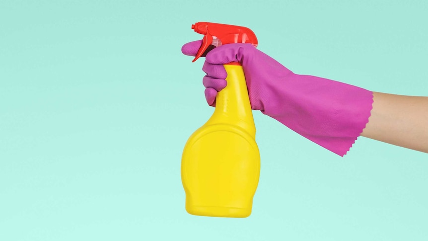 Hand with rubber glove holding spray bottle with blank background for a story about cleaning your home without harsh chemicals.