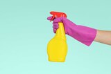 Hand with rubber glove holding spray bottle with blank background for a story about cleaning your home without harsh chemicals.