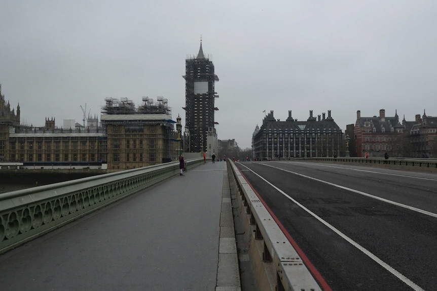 A woman takes a selfie on a near empty Westminster Bridge backdropped by the scaffolded Houses of Parliament in London.