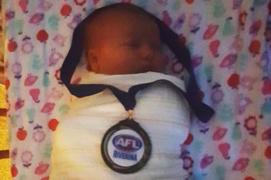 Baby Penny Irwin wearing father Neil's AFL medal
