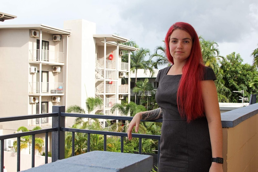 Darwin woman Brooke Ottley stands on her balcony looking at the camera.