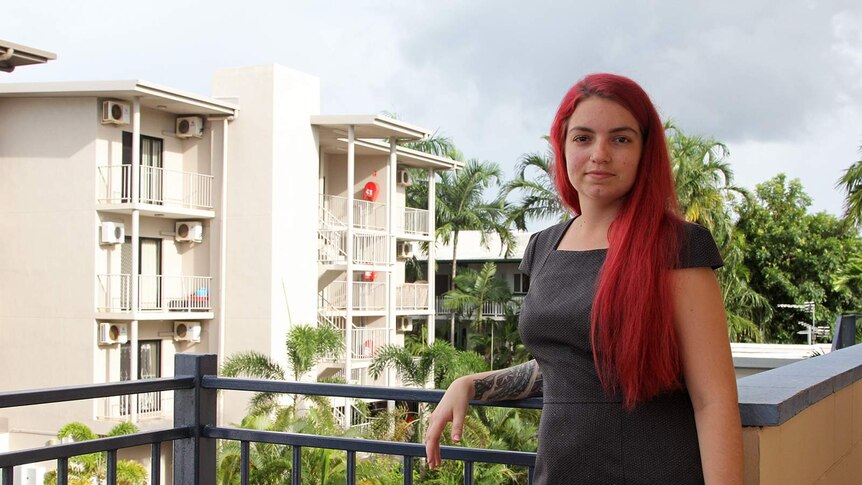 Darwin woman Brooke Ottley stands on her balcony looking at the camera.