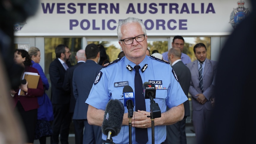 A police officer stands in front of a microphone