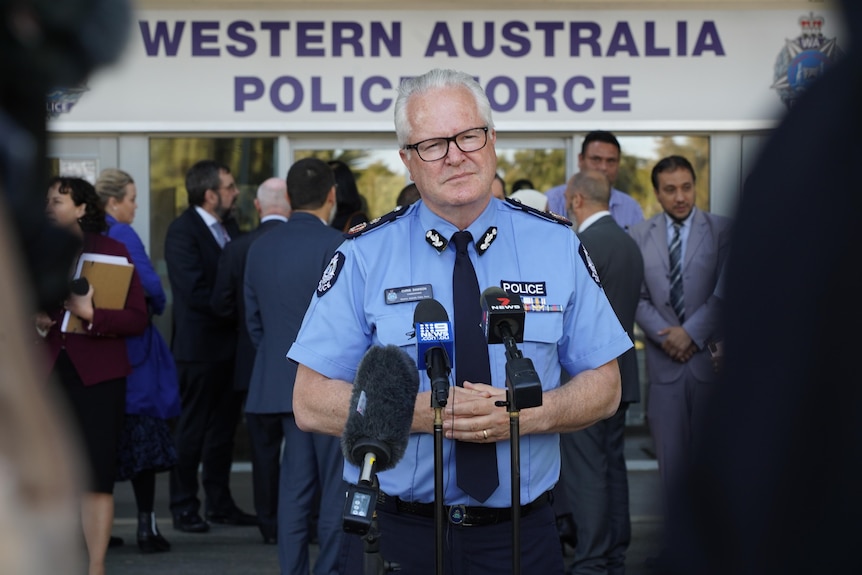 A police officer stands in front of a microphone