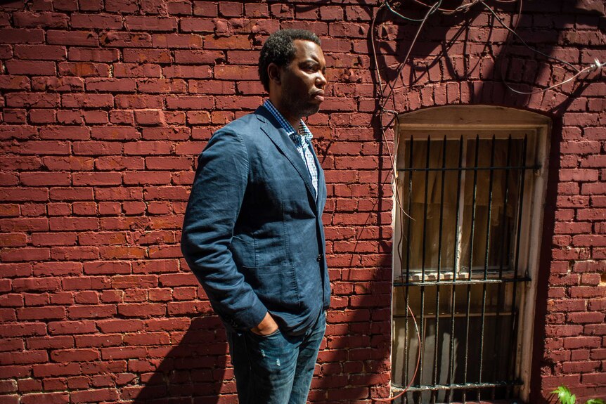 Ta-Nehisi Coates stands against a brick wall.