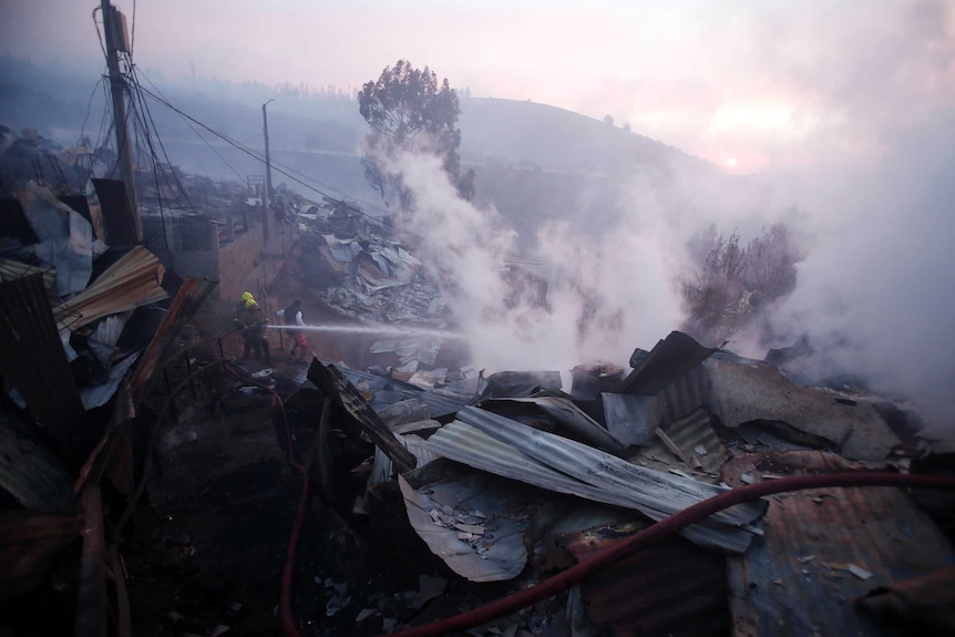 Firefighters hosing down a blaze amid the rubble of destroyed houses.
