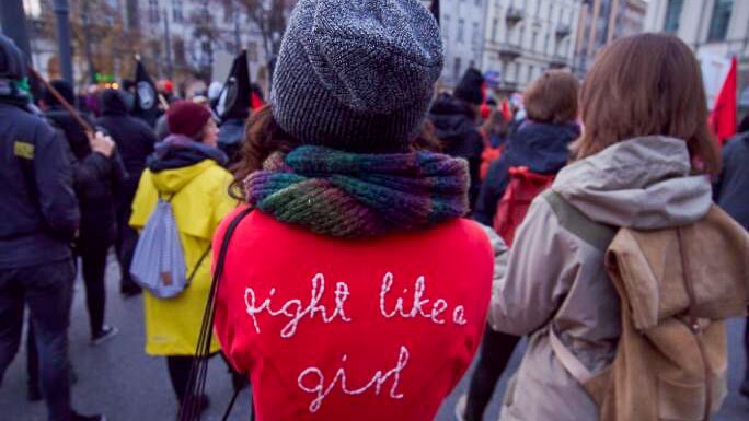 A woman in a red jumpsuit with "fight like a girl"