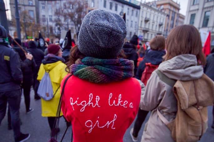 A woman in a red jumpsuit with "fight like a girl"