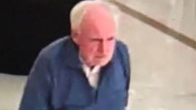 A still image taken from CCTV footage showing elderly man Alexander Henderson walking in a shopping centre wearing a blue shirt.