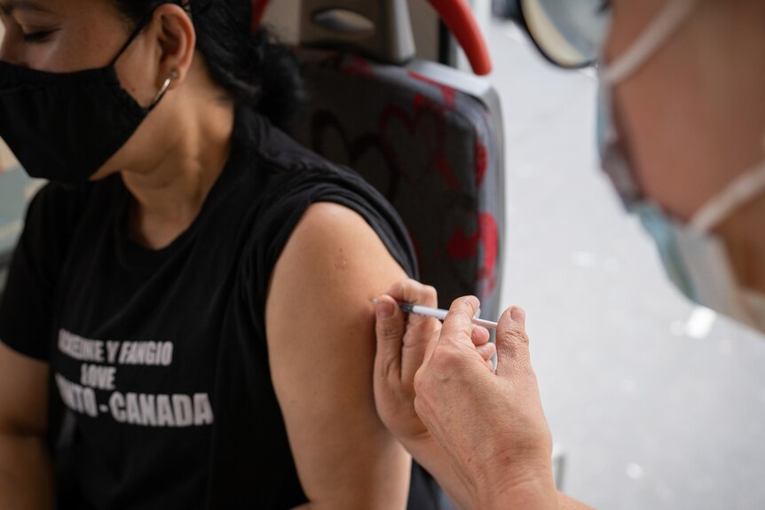 A woman receives a shot of the Pfizer/BioNTech vaccine at a mobile vaccination bus in London.