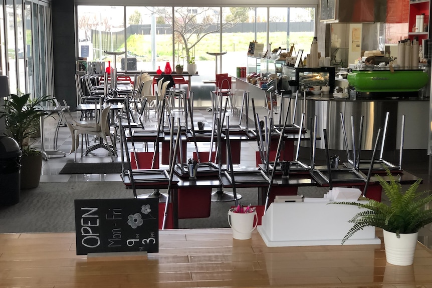 A closed cafe with chairs stacked on the tables.