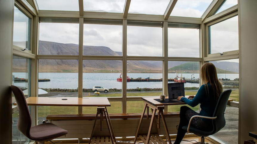 Lady sitting at a desk on her laptop with a view overlooking a lake