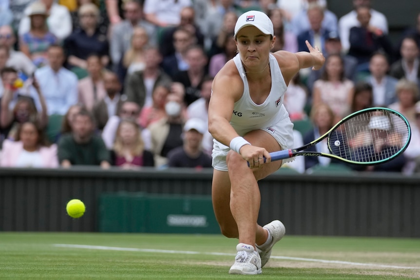 Ash Barty lunges forward to make a backhand return as the ball bounces low off the grass in the Wimbledon final.