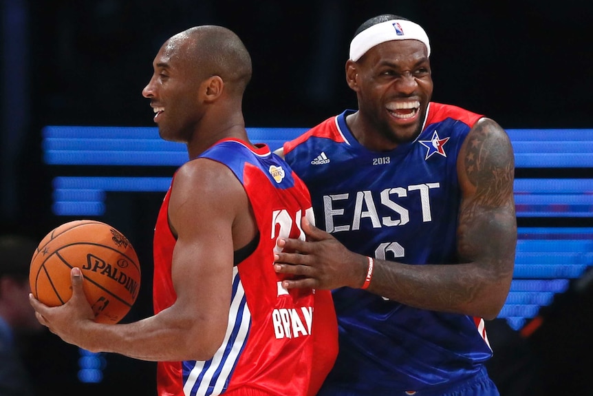 LeBron James laughs as he pats Kobe Bryant, holding a basketball, on the back during the NBA All-Star game.