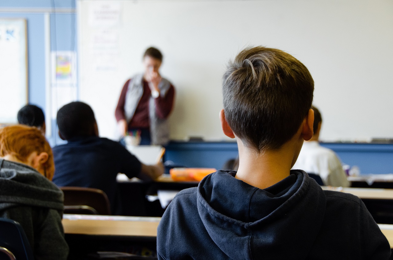 一个男孩面对着一位站在黑板前的老师。