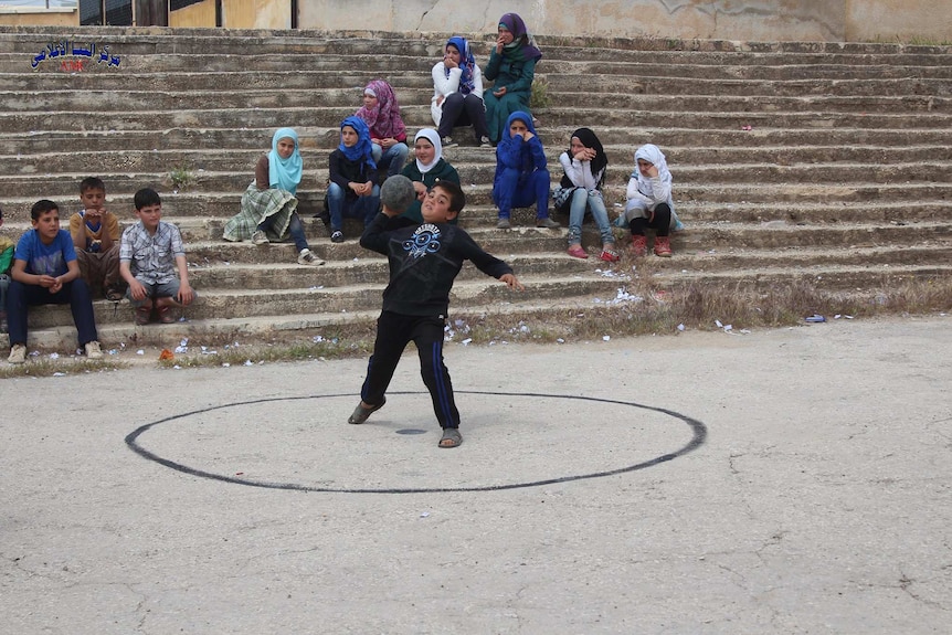 A boy competes in shot put in Aleppo