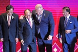 Scott Morrison hugs Vietnam's Prime Minister Nguyen Xuan Phuc in front of a pink and purple background.