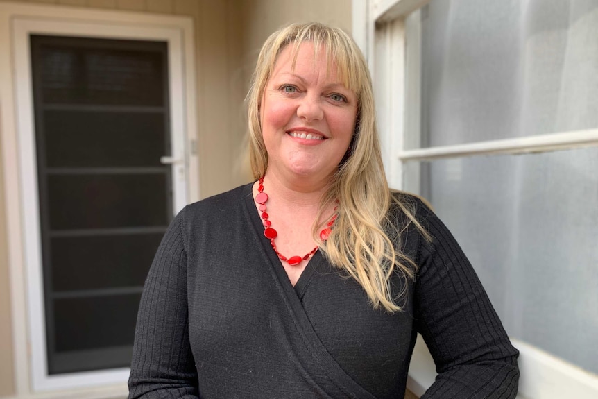 Emma Harper stands outside her house and smiles for the camera.