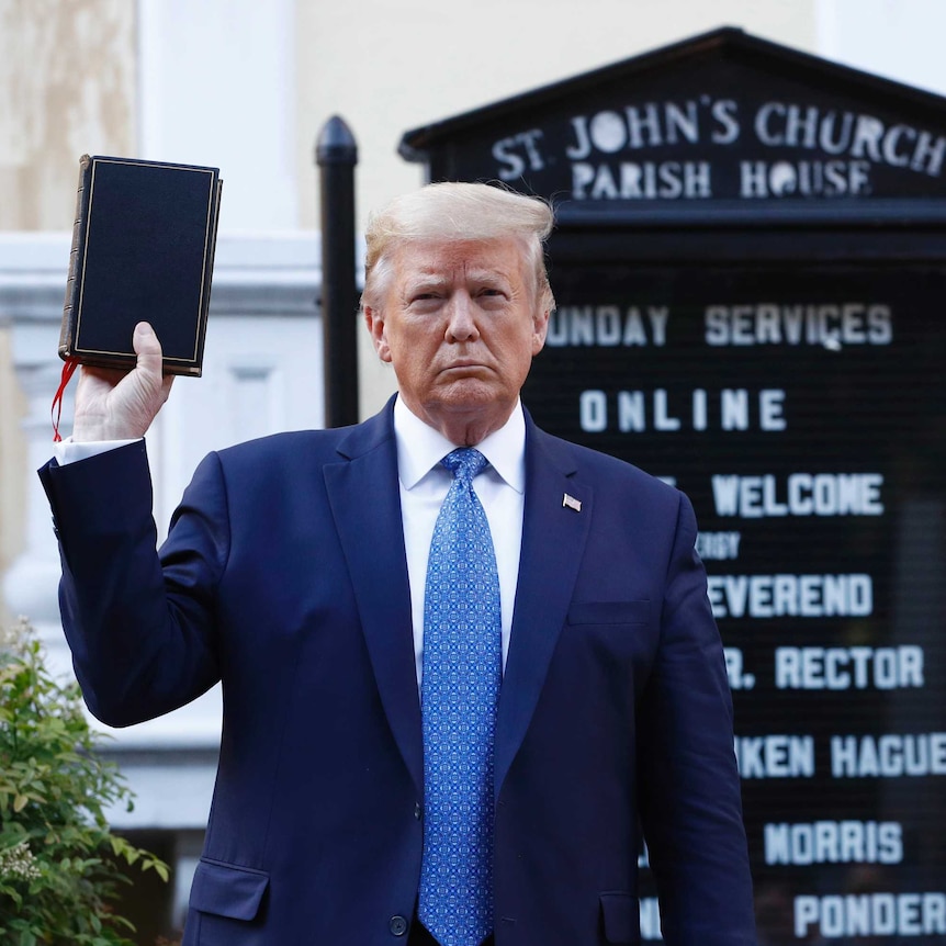 Donald Trump holds up a bible in front of a church