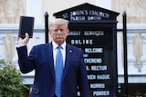 Donald Trump holds up a bible in front of a church
