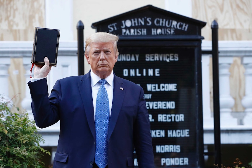 Donald Trump holds up a bible in front of a church