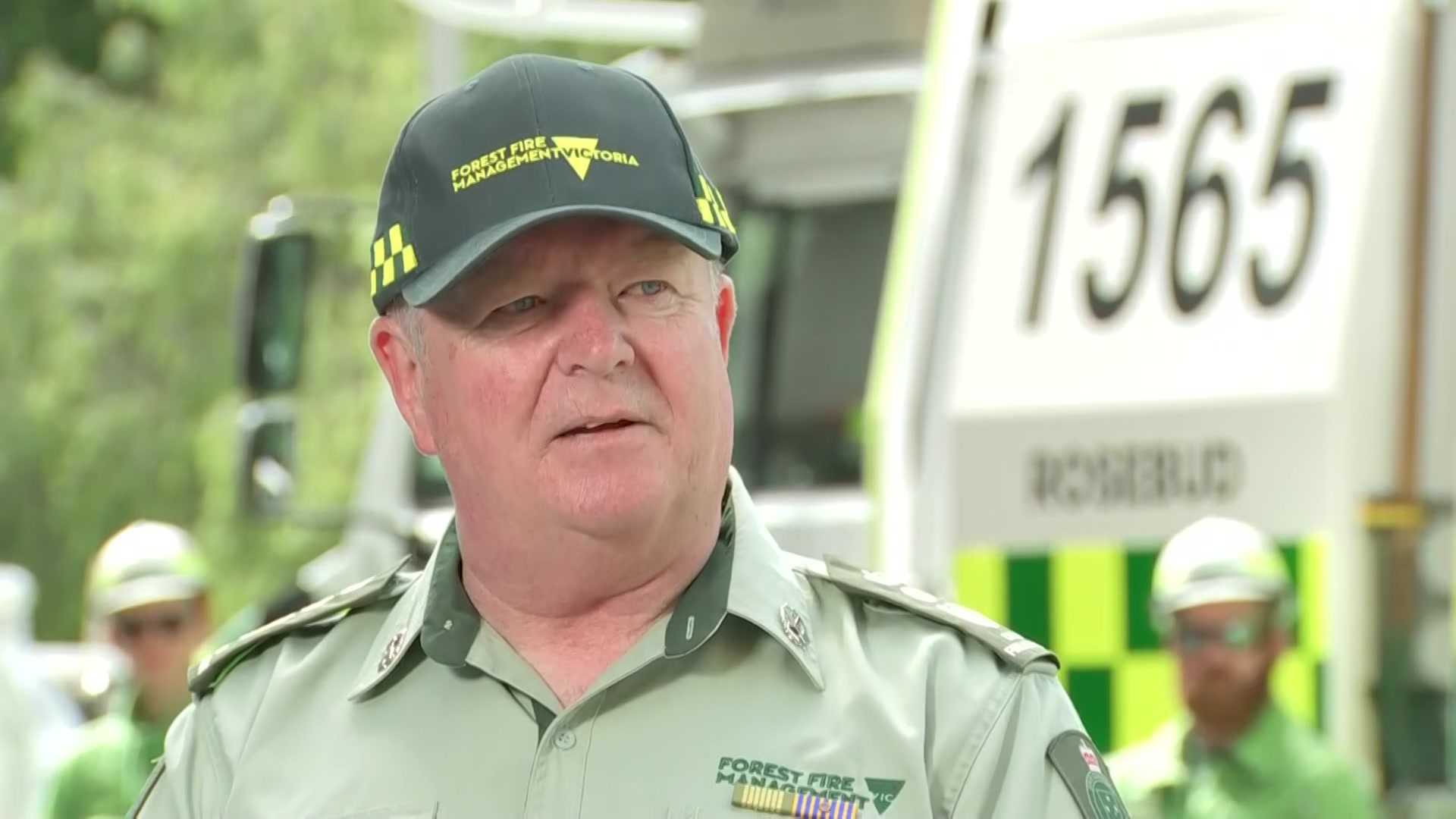victoria's Chief Fire Officer Chris Hardman stands outdoors talking to the media wearing a cap