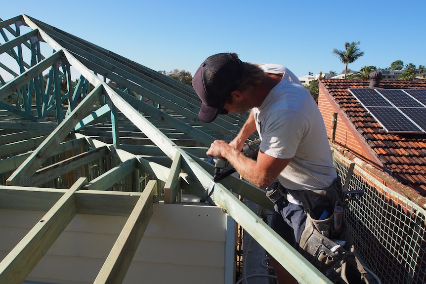 tradie drills nails into roof