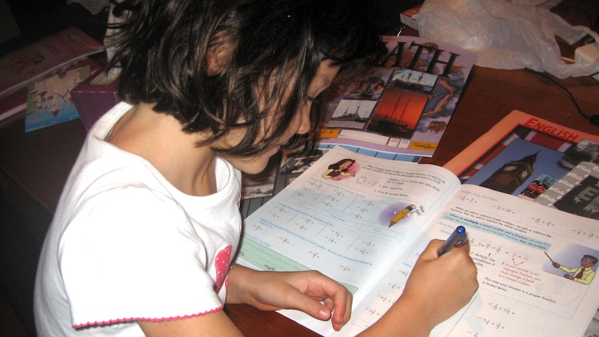 A girl studies with home-schooling textbooks