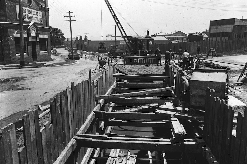 Men work on a construction site in a black and white photo