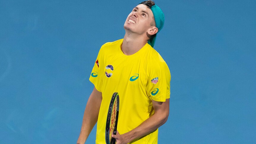 Alex de Minaur looks to the sky in frustration while holding his racquet.