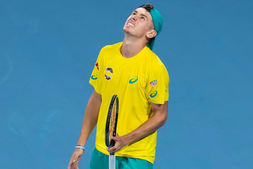 Alex de Minaur looks to the sky in frustration while holding his racquet.