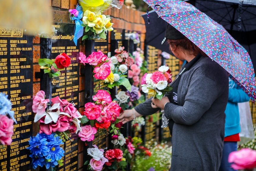 A woman holds a bouquet of flowers at the memorial wall.