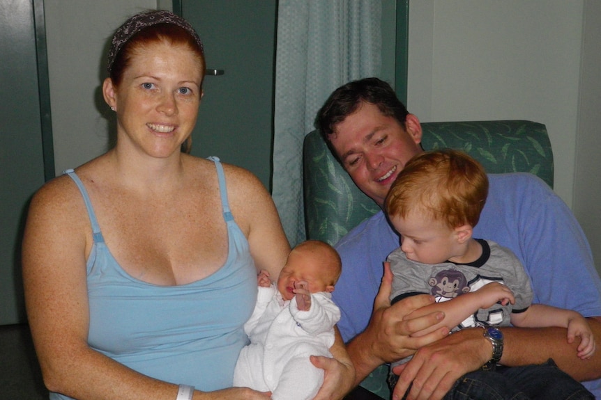 A smiling woman with a newborn baby and her partner with their toddler.