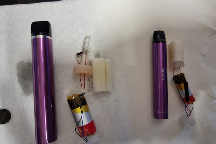 An image of a two cylindrical vaping devices which have been taken apart and placed alongside their components