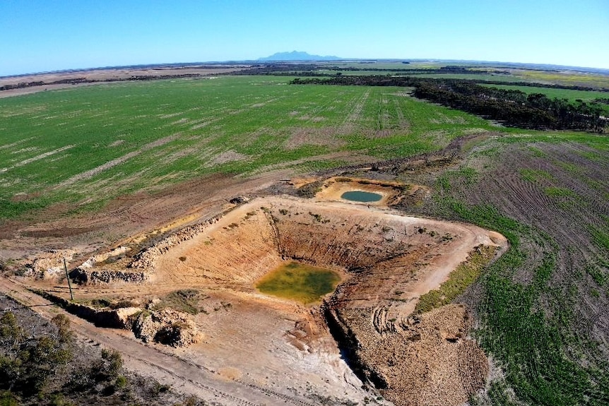 An aerial shot of a large dam next to a much smaller dam, with a small amount of water in the bottom.