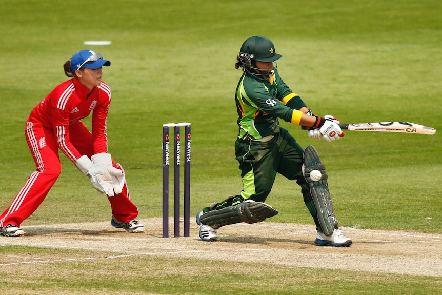 A Pakistani female crickter tries to play a shot as she is hit by the ball in the pads, while the England wicketkeeper looks on.